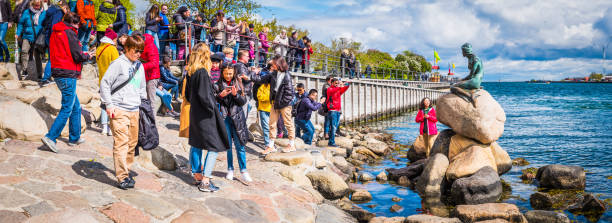 multidões do porto de copenhaga dos turistas que visitam a estátua pequena dinamarca da sereia - denmark danish culture copenhagen sculpture - fotografias e filmes do acervo