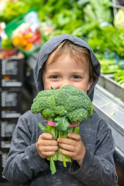 trzyletni chłopiec trzyma brokuły w supermarkecie greengrocer sekcji nawy - children only healthy lifestyle vertical close up zdjęcia i obrazy z banku zdjęć