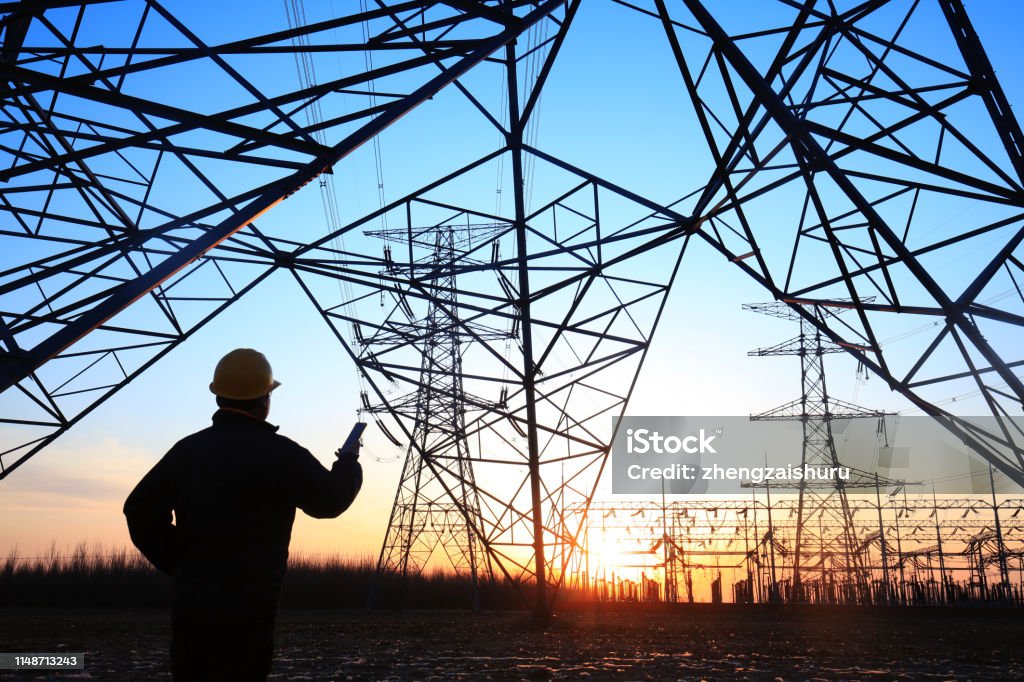 Electricity workers and pylon silhouette Power Line Stock Photo