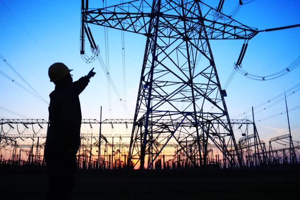 istock Electricity workers and pylon silhouette 1148713258
