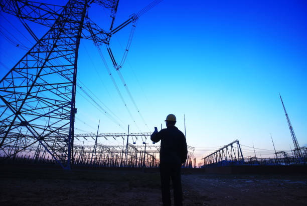 istock Electricity workers and pylon silhouette 1148713286
