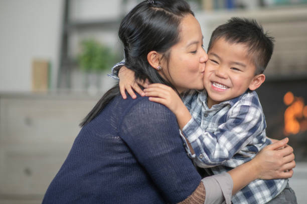 madre besando a un hijo en la mejilla - filipino fotografías e imágenes de stock