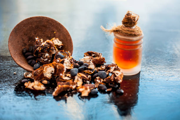 istock Tamarind or imli or amli in a clay bowl along with its roasted seeds and extract essential oil in a glass bottle on wooden surface. 1148714414
