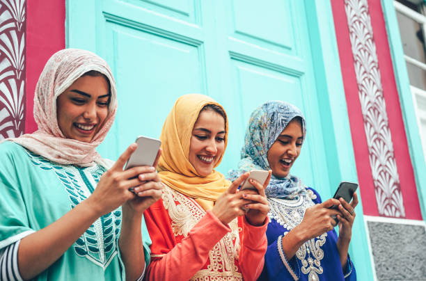 giovane amico musulmano che utilizza smartphone mobili nel college - ragazze arabiane felici dipendenti dalle nuove tecnologie app cellulare per i social media - millennial, religione, generazione z e concetto tecnologico - islam child indian culture ethnic foto e immagini stock