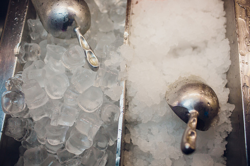 silver ice scoops in a large ice-filled bucket