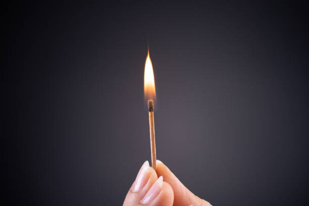 close up woman hand holding a burning match. - fire match women flame imagens e fotografias de stock