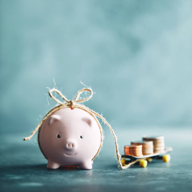 istock Little pink piggy bank pulling a skateboard with money 1148728522