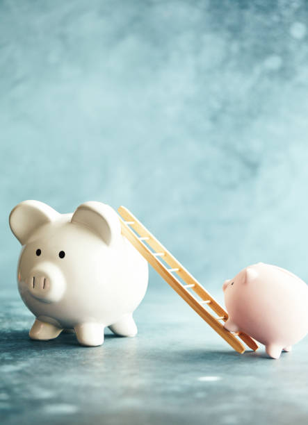 istock Piggy banks with ladder in blue setting 1148728591