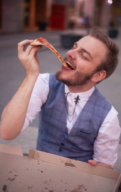 istock one young businessman eating pizza cut. 1148729805
