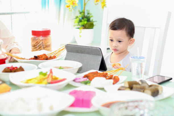 A Malay Muslim toddler watching a digital tablet on Hari Raya Aidilfitri/ Eid-Ul-Fitr while waiting for the meals to be prepared.