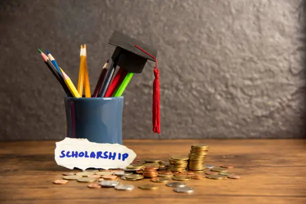 Photo of Education and back to school concept with graduation cap on pencils colour in a pencil case on dark background  scholarships with money coin