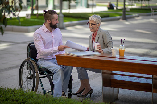 Disability man with beautiful mature gray hair woman on meeting out of office