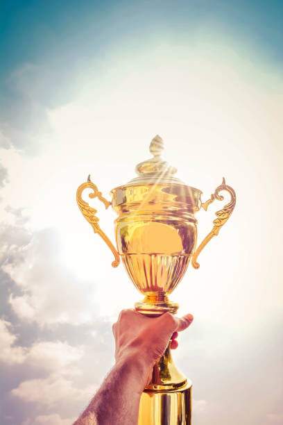 istock Holding up a gold trophy cup as a winner 1148746659