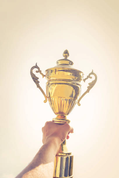 istock Holding up a gold trophy cup as a winner 1148746660