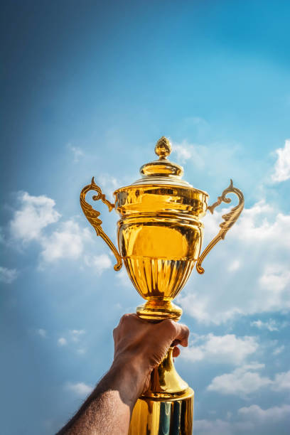 istock Holding up a gold trophy cup as a winner 1148746665