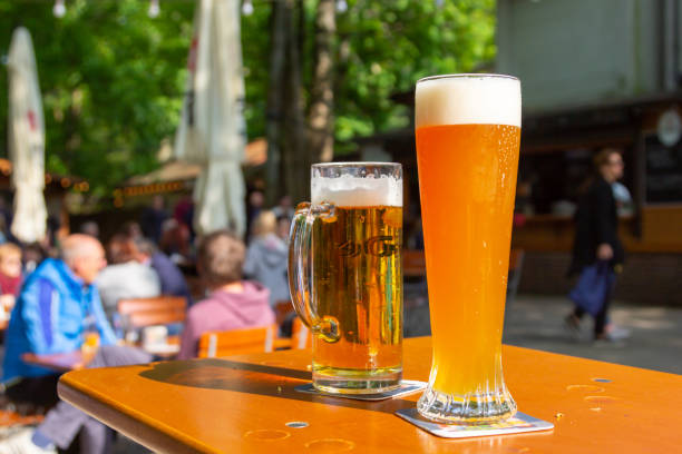 A wheat beer and a pils are standing on a table in a beer garden