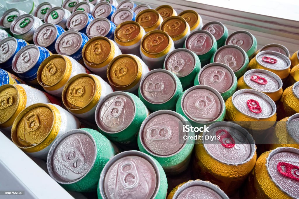 Latas de cerveja frescas da geladeira. Lotes de latas de alumínio no gelo no refrigerador aberto. Gotas da água em uma lata fria da bebida - Foto de stock de Lata - Recipiente royalty-free