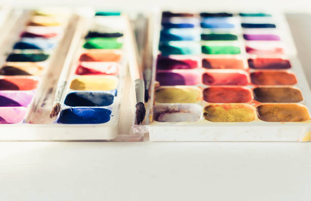 istock Watercolor paint and brushes well used on white wooden table with copy space for text 1148757093