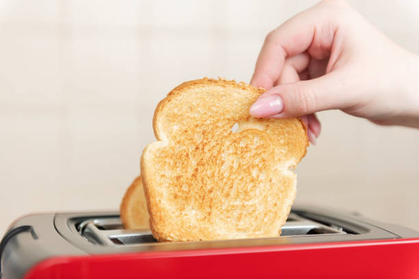 istock Red toaster with toasted bread for breakfast inside. Hands Girl pulls out ready toasts. 1148757180