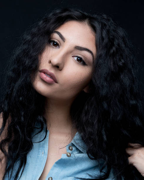 istock Good looking female with curly hair on black background 1148759072
