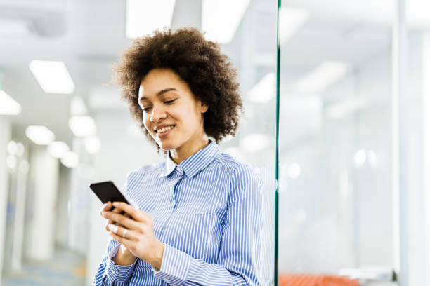 istock Happy black businesswoman using cell phone in a hallway. 1148759912