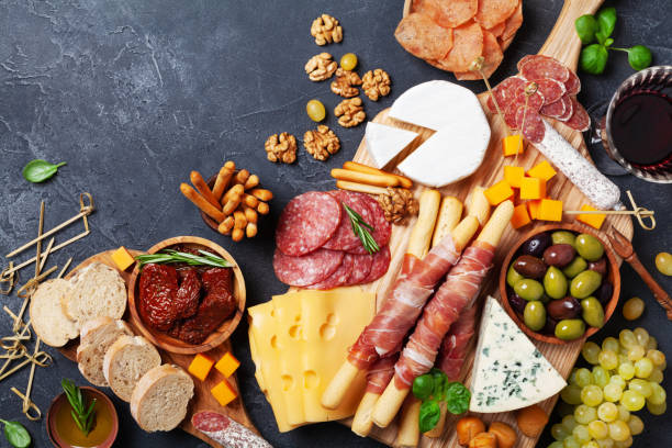Italian appetizers or antipasto set with gourmet food on kitchen table top view. Mixed delicatessen of cheese and meat snacks with red wine. Italian appetizers or antipasto set with gourmet food on stone kitchen table top view. Mixed delicatessen of cheese and meat snacks with red wine. prosciutto brie stock pictures, royalty-free photos & images