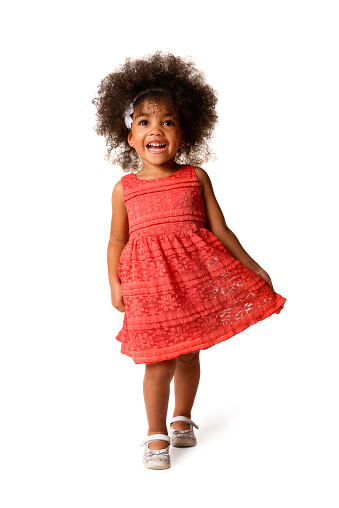 Full length portrait of cheerful african american little girl in dress of the color of the year 2019 living coral, isolated over white background