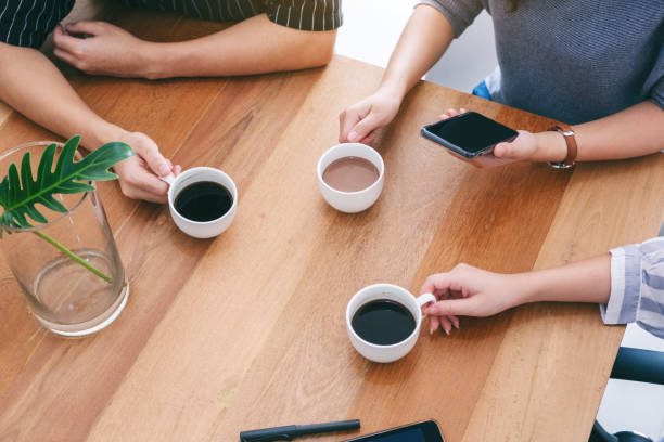 istock three people holding coffee cups to drink on wooden table 1148761557