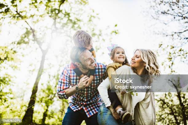 Sotto Vista Della Famiglia Giocosa Che Si Diverte Mentre Fa Il Piggybacking Nella Natura - Fotografie stock e altre immagini di Famiglia