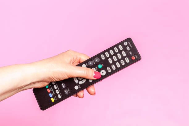 istock woman hand holding remote control, on pink background 1148763731