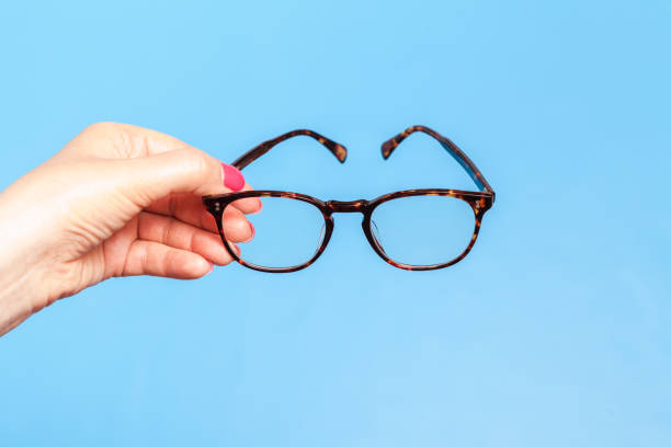 istock Woman hand holding spectacles on blue background 1148763739