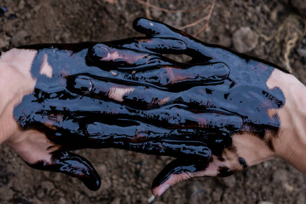 oil leaking. Very dirty hand.Stain hands showing thumbs up with black oil on soil background.