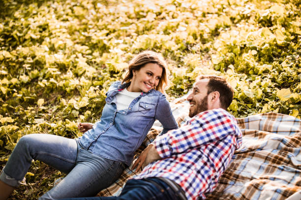 istock Young happy couple talking while relaxing on blanket in nature. 1148764574