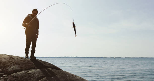 Man fishing with a rod from a rock spot, in Hordaland, Norway