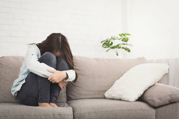 istock Unhappy girl sitting on sofa feeling lonely 1148768973