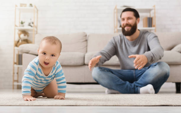 istock Adorable baby boy crawling on floor with dad 1148772302