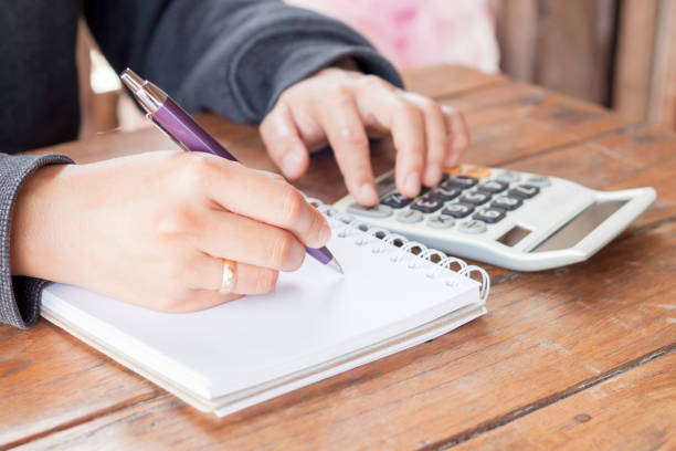 istock Close-Up Of Person Writing In Book While Using Calculator 1148775586