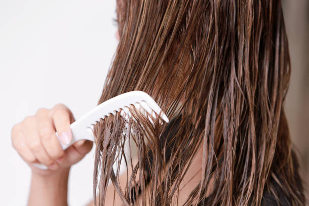 Close-Up Of Woman Combing Hair Over White Background stock photo