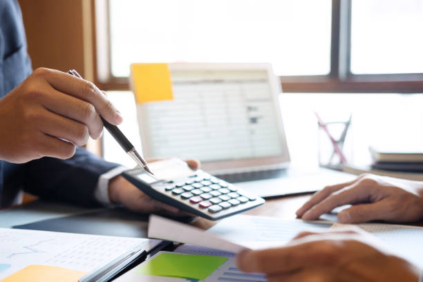 istock Midsection Of Businessmen Working Over Graph On Table 1148785474