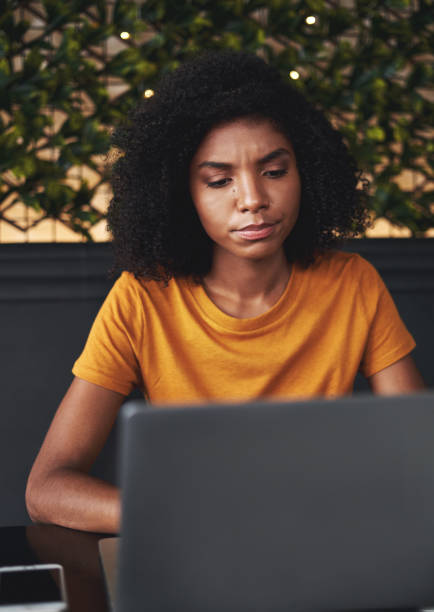 istock Serious young woman using laptop in cafe 1148786740