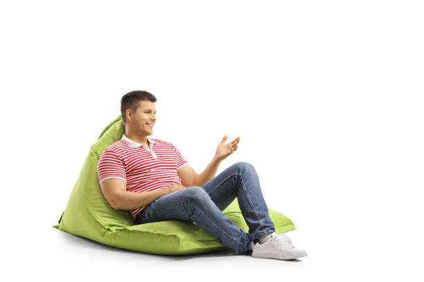 istock Young man sitting on a green bean bag and gesturing with hand 1148790047