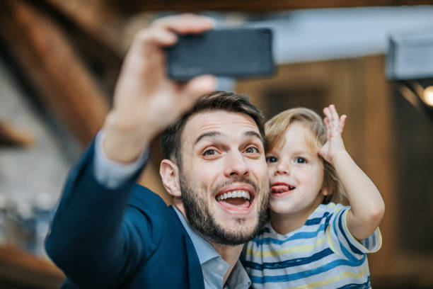 istock Happy father and son making faces while taking a selfie with cell phone. 1148791874
