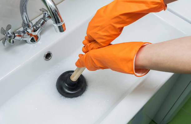 pessoa em luvas alaranjadas protetoras que desbloqueiam um dissipador obstruído com atuador ou a bomba de borracha. close-up, foco seletivo. - plunger - fotografias e filmes do acervo