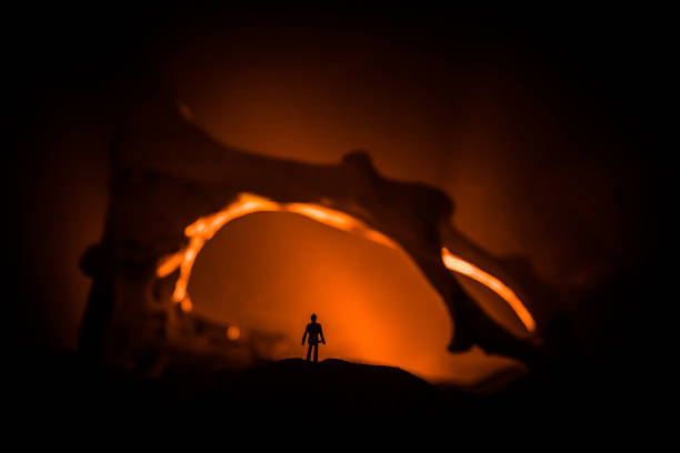 istock Artwork decoration with animal bone. Silhouette in an underground abandoned crypt. man standing in front of a cave entrance 1148795040