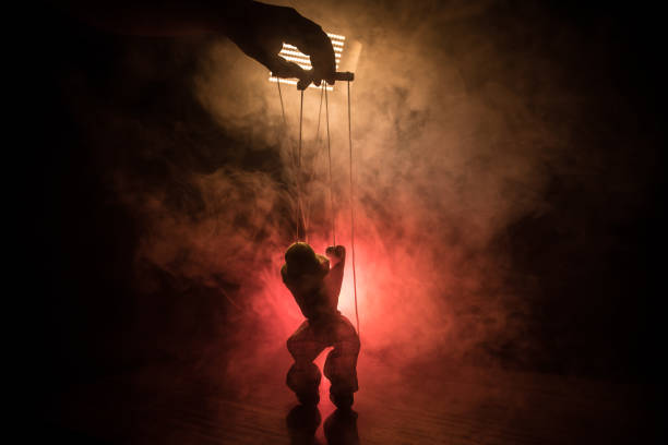istock Concept of manipulation. Hand holds strings for manipulation. The hand controls the puppet strings on a dark foggy background. 1148795481