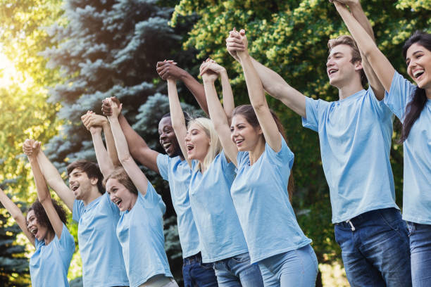 istock Group of young volunteers join hands in park 1148796642