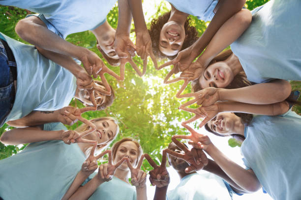 Group of friends standing in circle and showing peace