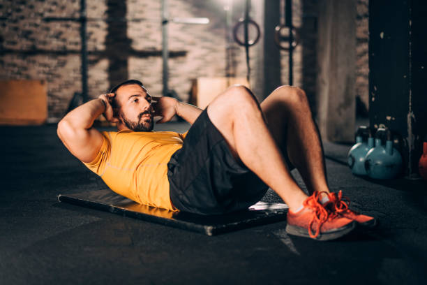 istock Young muscular athlete doing a sit ups workout in a gym 1148797349