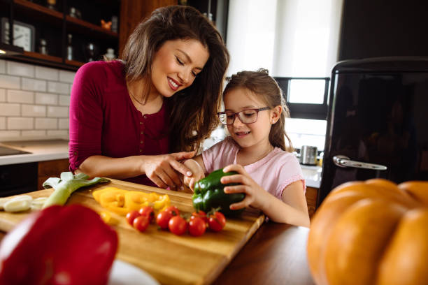 istock Mother and daughter cutting vegetable in the kitchen 1148798142
