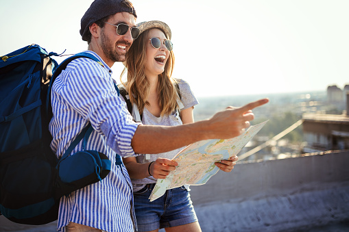 Happy young couple of travellers holding map in hands on vacation